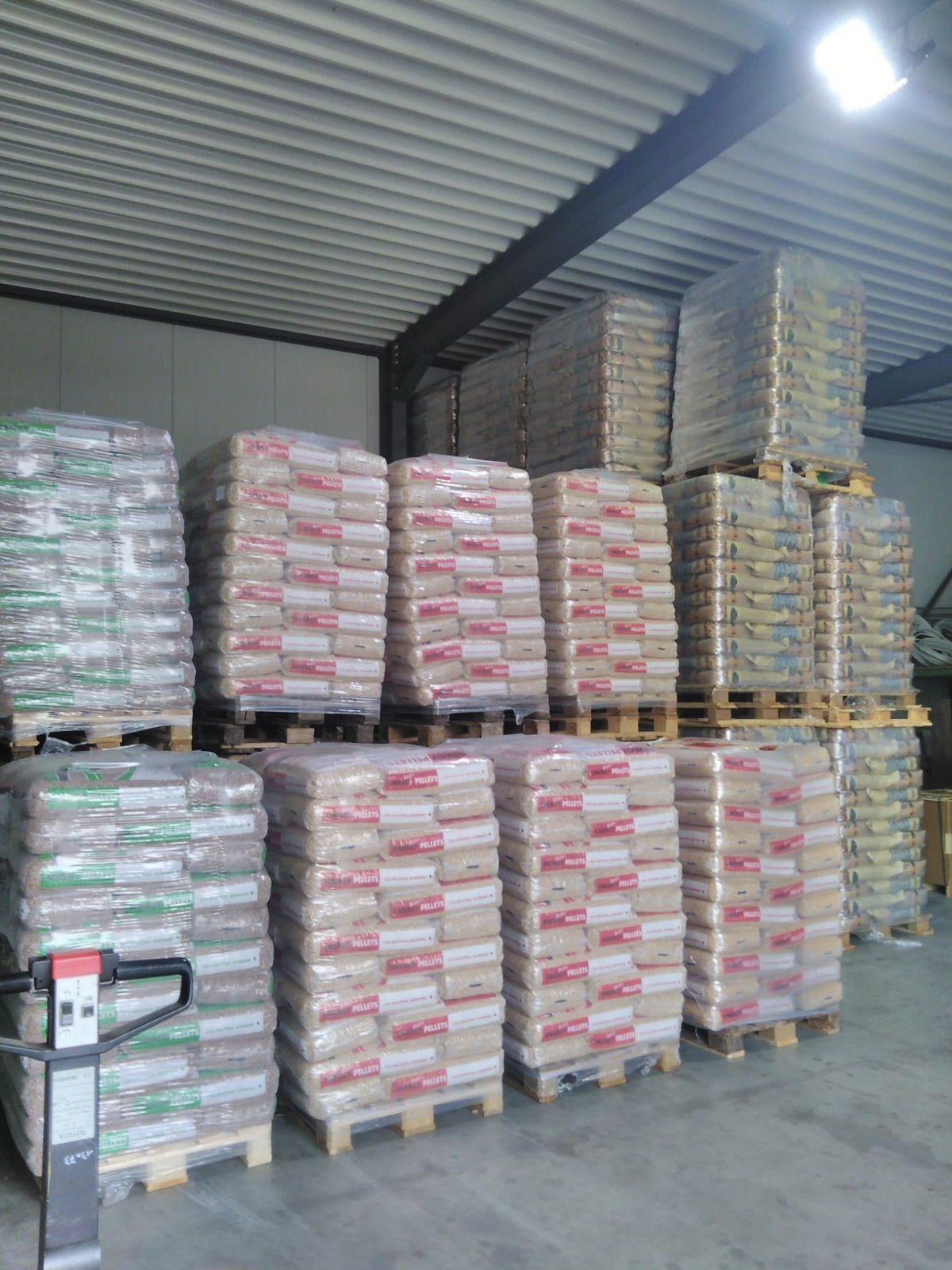 Warehouse with pallets of bagged wood pellets and a delivery truck